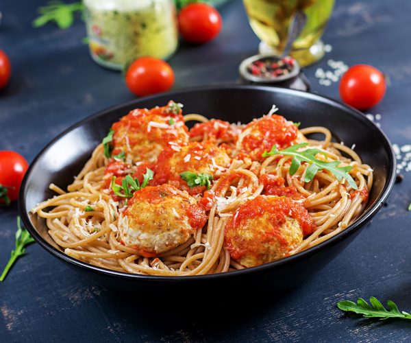 Italian pasta. Spaghetti with meatballs and parmesan cheese in black plate on dark rustic wood background.  Dinner. Slow food concept
